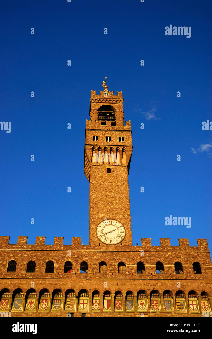 Palazzo Vecchio, tower with clock and emblems under blue sky, Florence, Tuscany, Italy, Europe Stock Photo