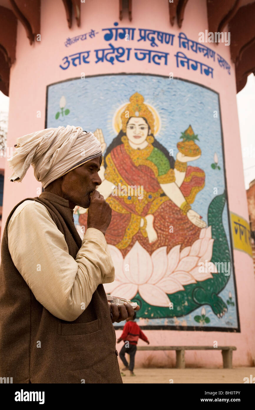 An Indian man wearing a turban stands by a column painted with an image of the Hindu goddess Ganga. Stock Photo
