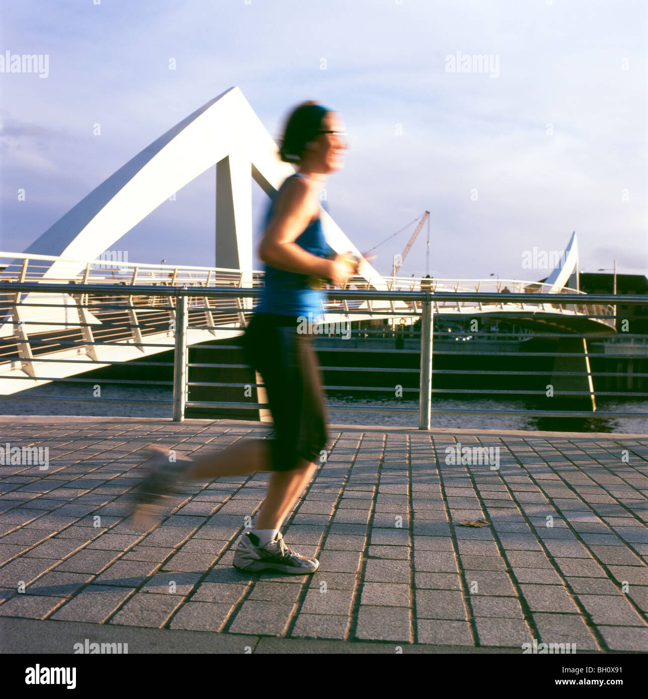 Young woman runner jogger on jog running jogging along the River Clyde past the Tradeston bridge in Glasgow Scotland UK Great Britain    KATHY DEWITT Stock Photo