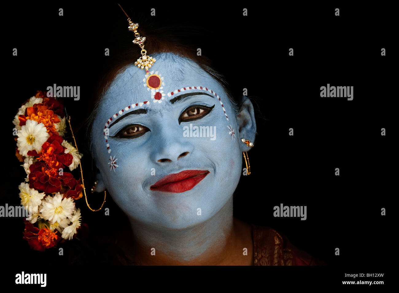 Indian girl face painted as the Hindu goddess Sita against a black
