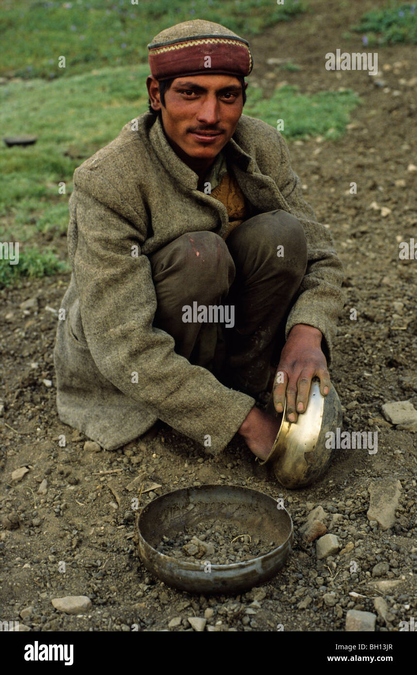Shepherd in Northern India cleaning his cooking utensils Stock Photo