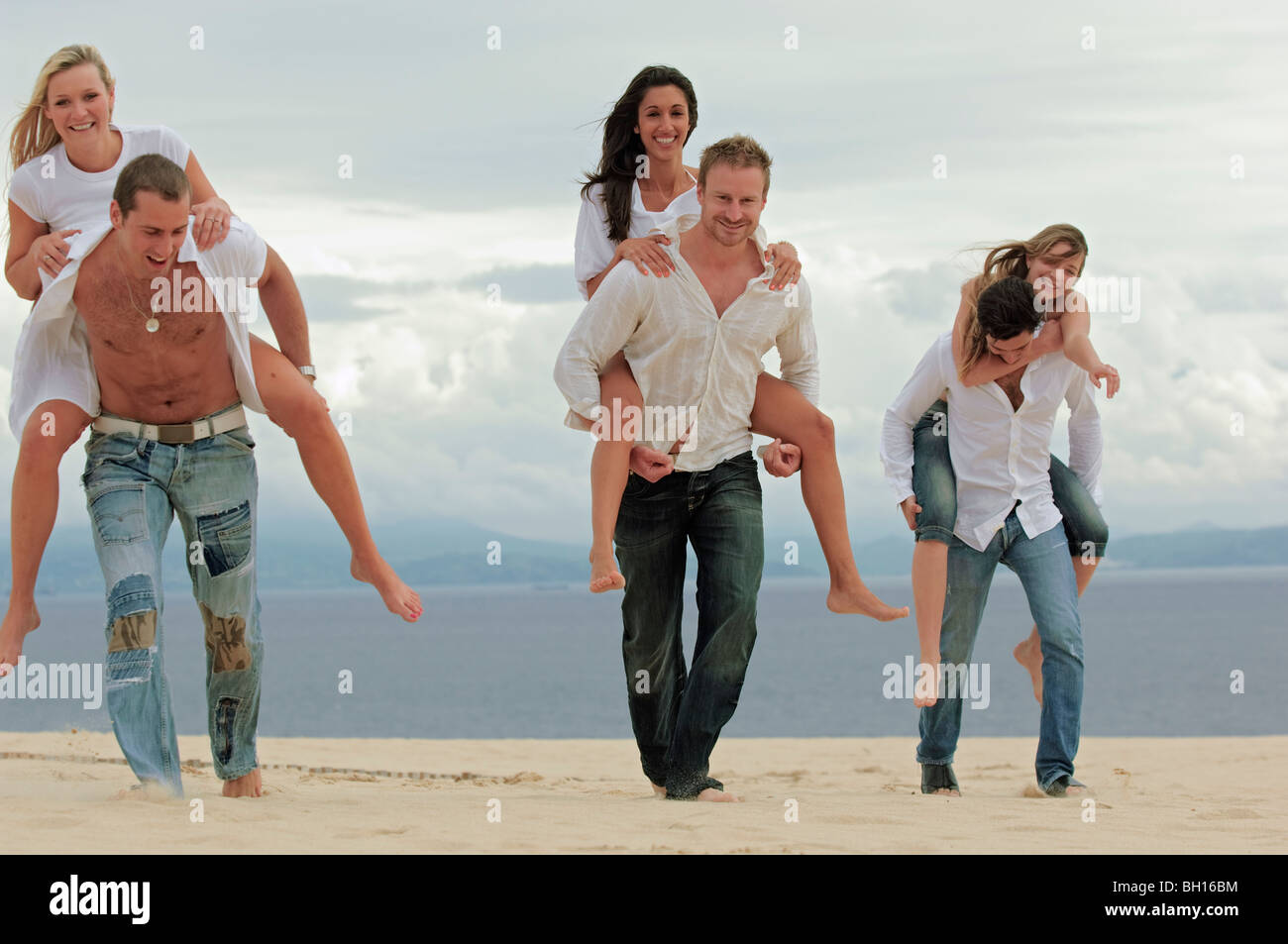 Young couples piggy-backing on beach Stock Photo - Alamy