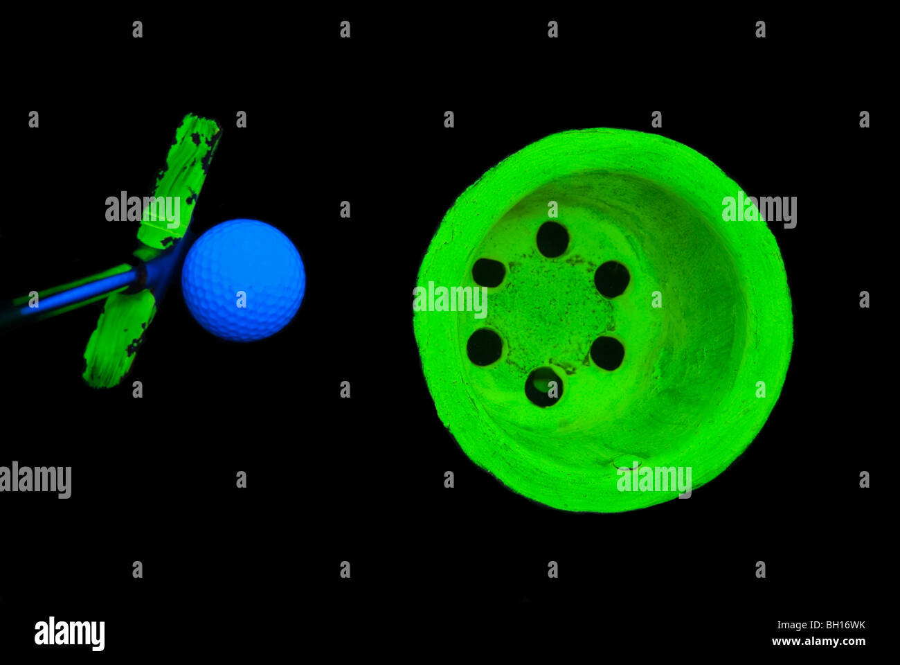 Stock photo of a putter, ball, and cup on an indoor day glo miniature golf course, shot under blacklight. Stock Photo