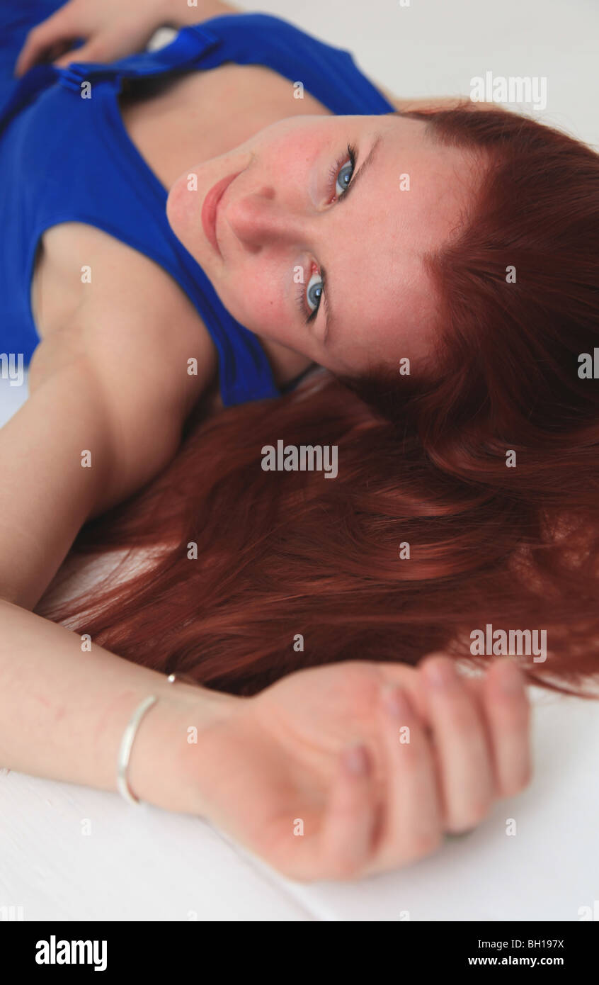 Woman with long red hair lying on white floor Stock Photo - Alamy