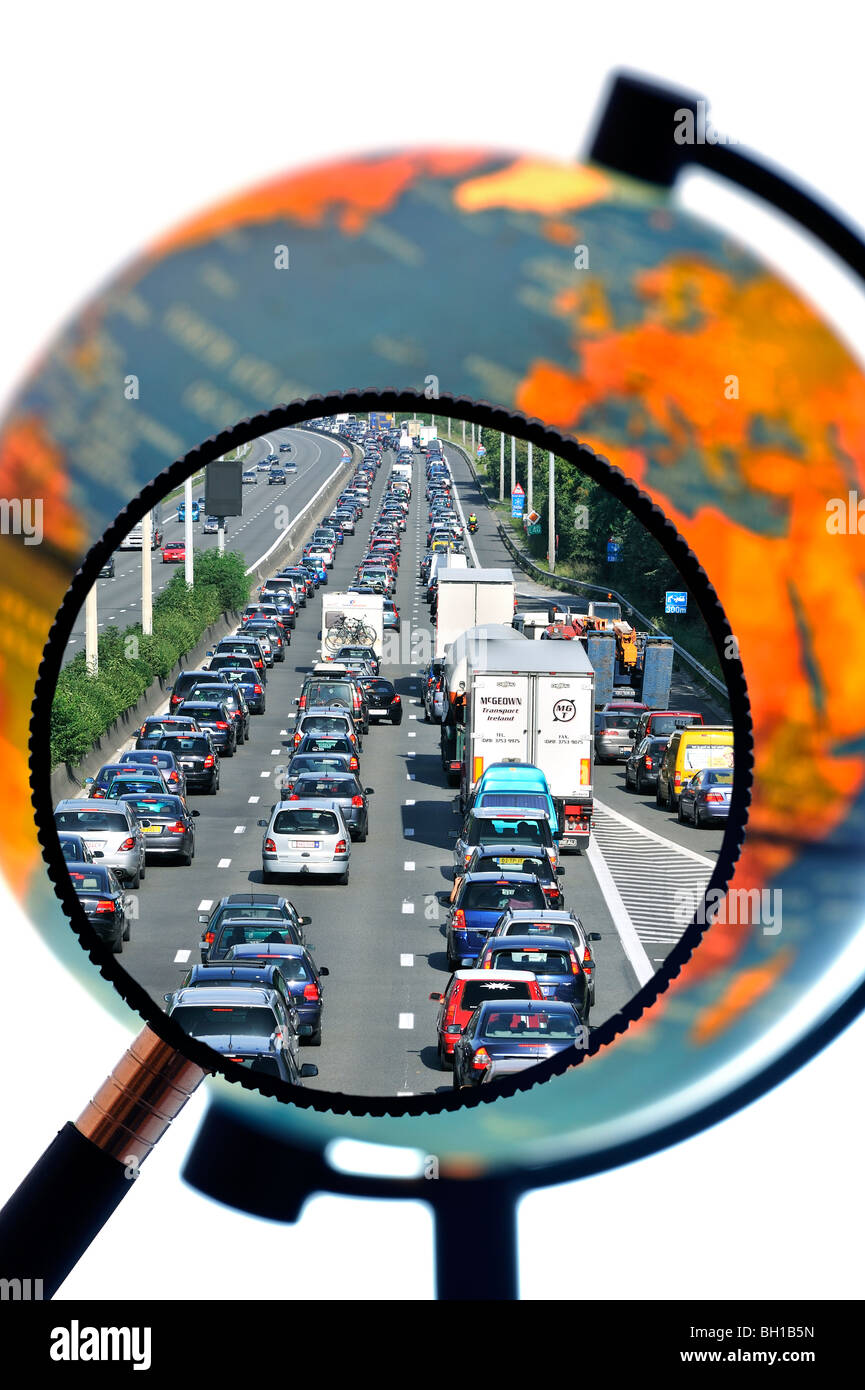 Cars in traffic jam on motorway during the summer holidays seen through magnifying glass held against illuminated globe Stock Photo