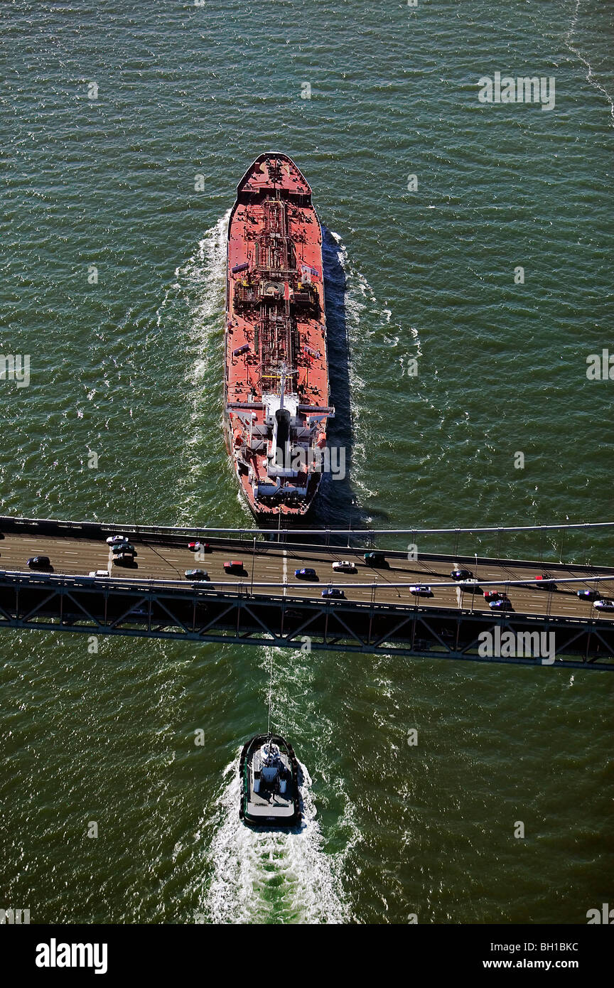 aerial view above oil tanker Seabulk America, Port Everglades escorted by tugboat passing under San Francisco Bay Bridge Stock Photo