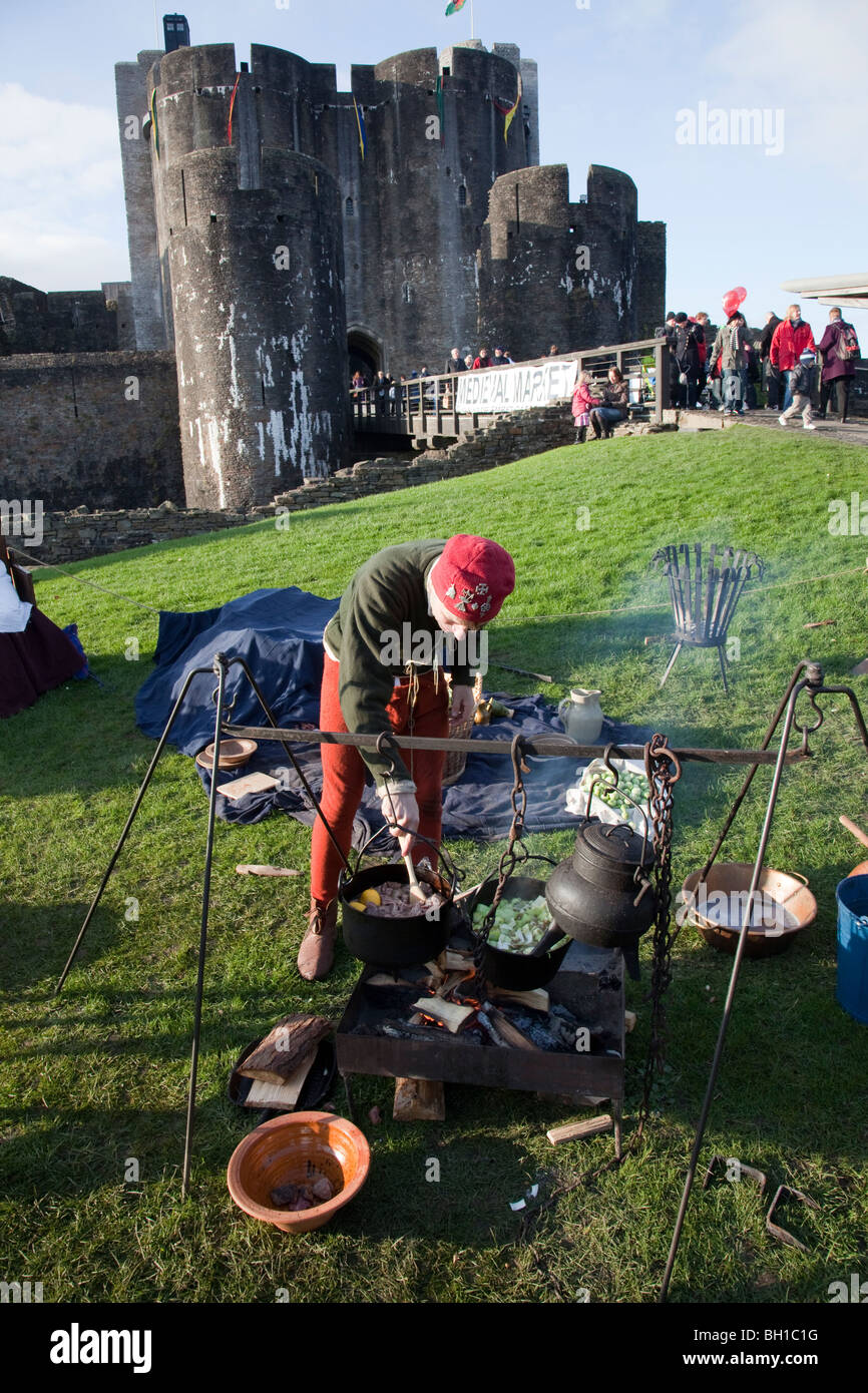 Man cooking stew over wood fire in demonstration at Mediaeval Christmas market Caerphilly Castle Wales UK Stock Photo