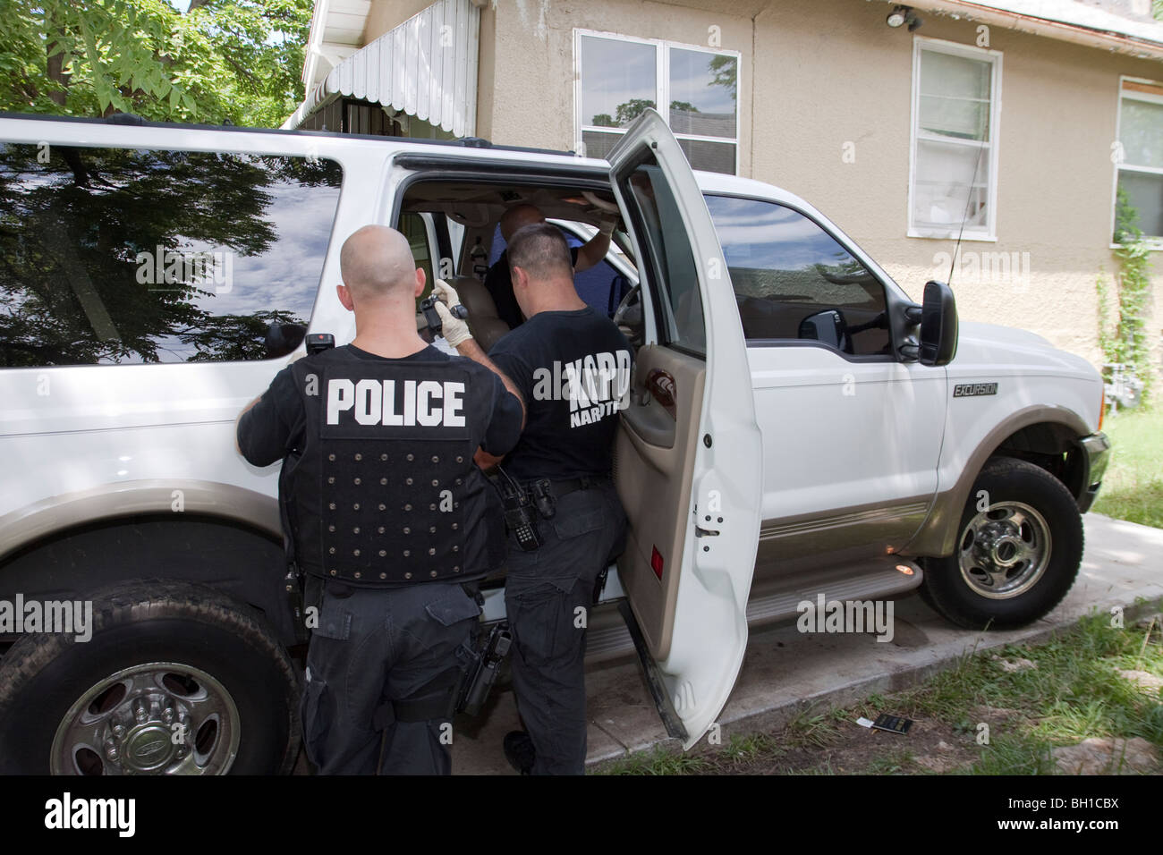 Police officers from SWAT team searching vehicle for drugs, cash and weapons. Search warrant. Street Narcotics Unit. Stock Photo