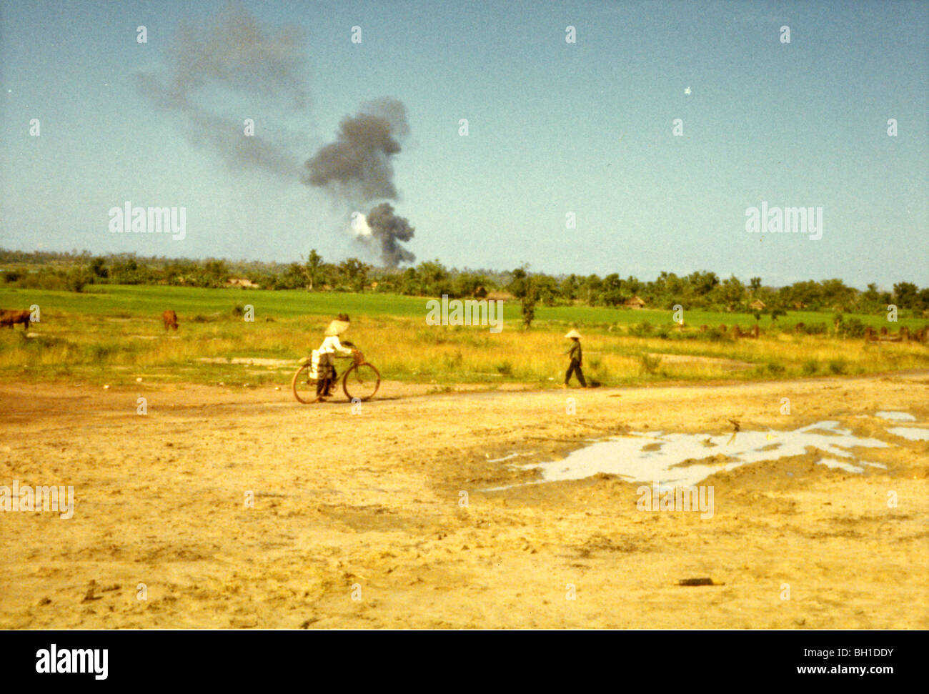Villagers watch a smoke plume rise from a battle. 1st Infantry Division operate during Vietnam War. Stock Photo