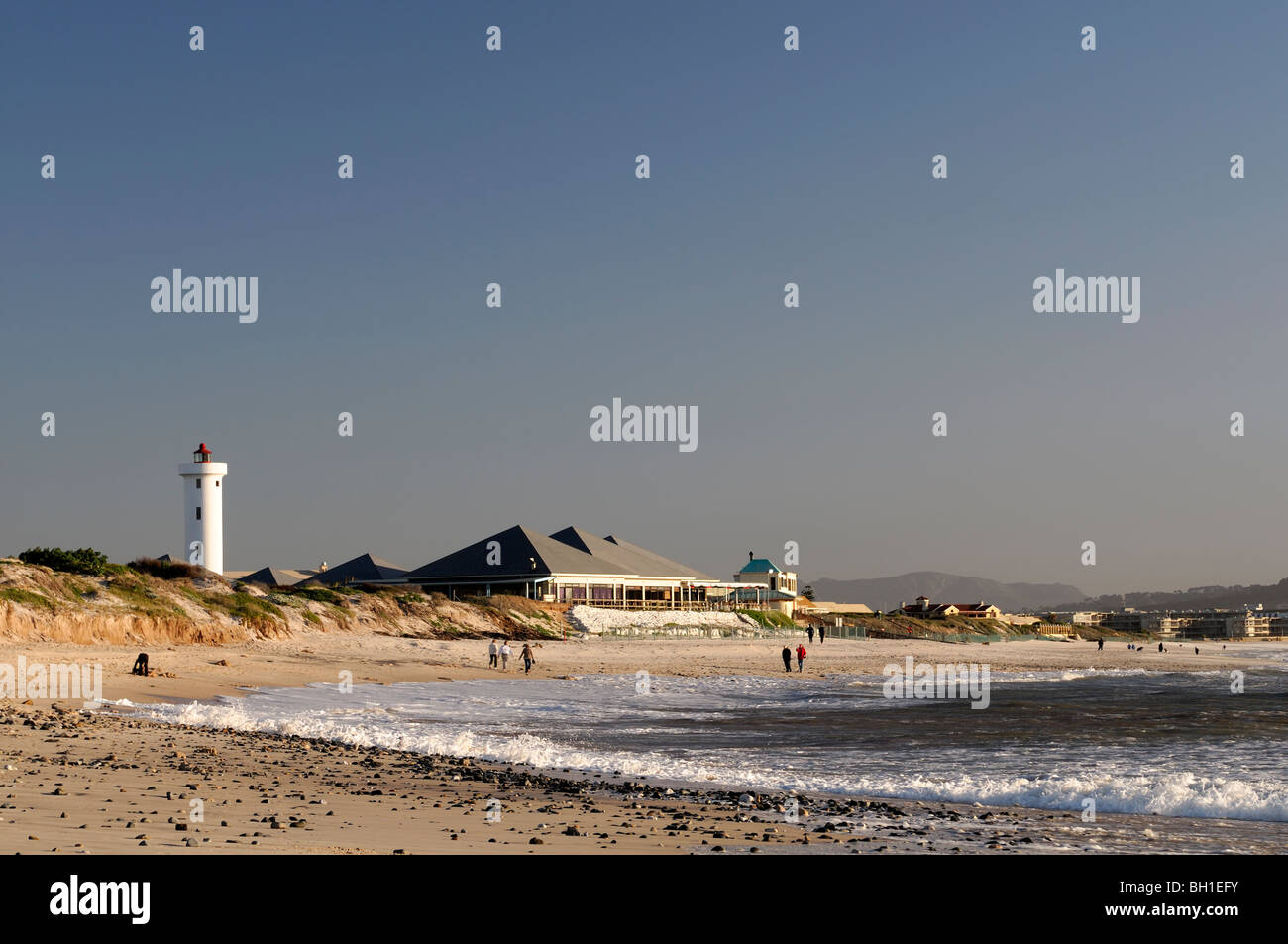 milnerton lighthouse and beach at dusk cape town south africa people walking on the beach Stock Photo