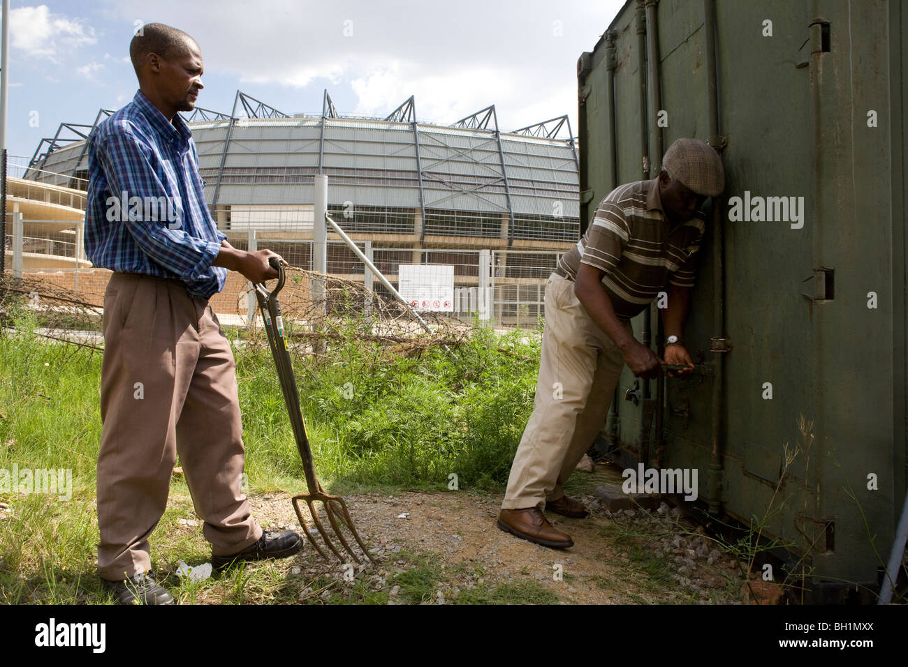 Men growing vegetables on allotment in the shadow of the Orlando Soccer City stadium in Soweto Stock Photo