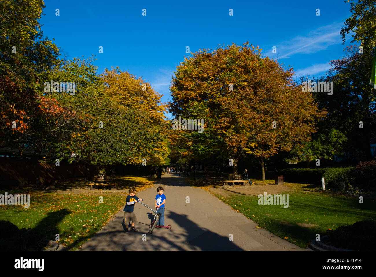 Two boys with kick scooters in Holland Walk Holland Park Kensington