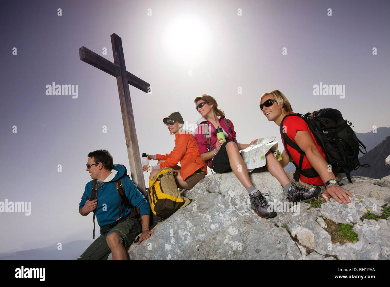 Group hikers near a summit cross, Wetterstein range, Bavaria, Germany Stock Photo