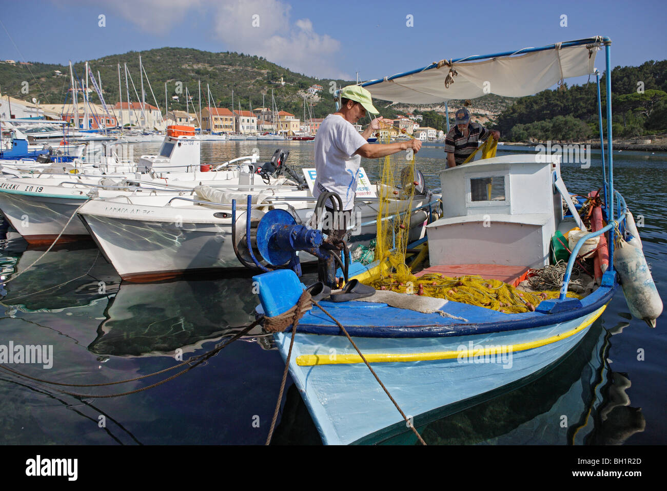 Two men working on a boat in Gaios harbour, Paxos, Ionian Islands, Greece Stock Photo