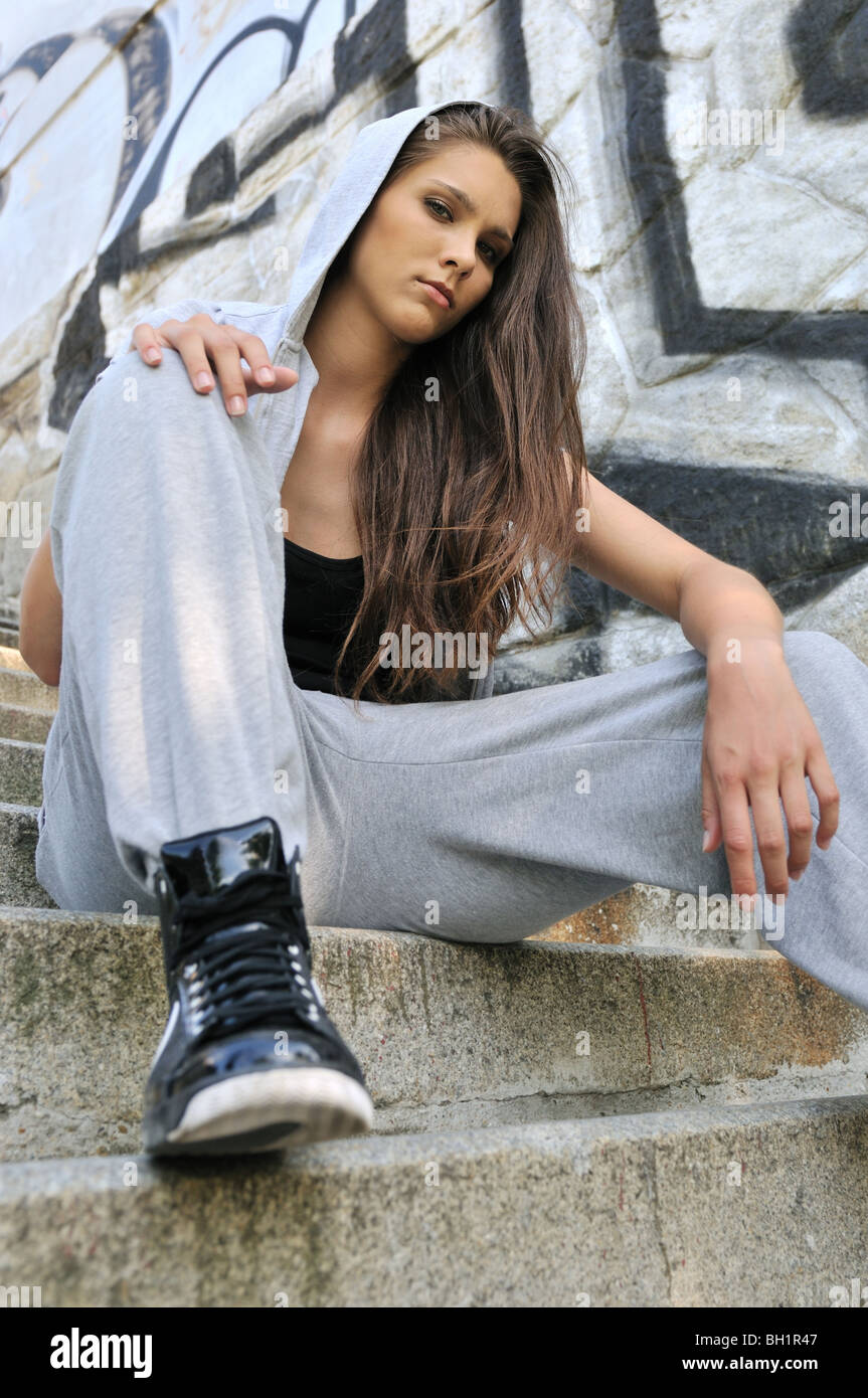 Youth collection - Young person (teenage girl) with hood in hip hop style posing in front of black and white graffity wall Stock Photo