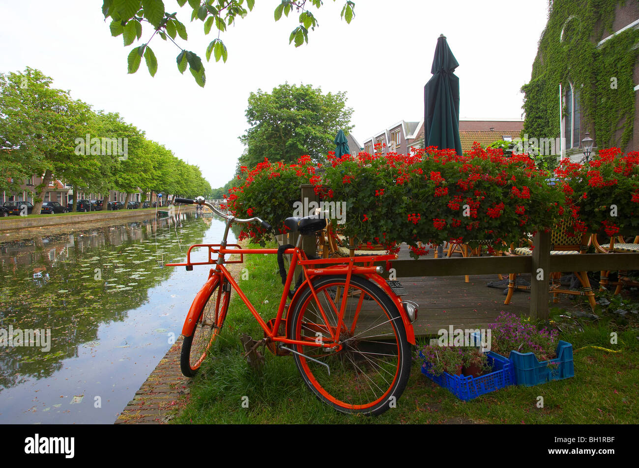 Red bicycle standing at the banks of a gracht canal, Weesp, Netherlands, Europe Stock Photo
