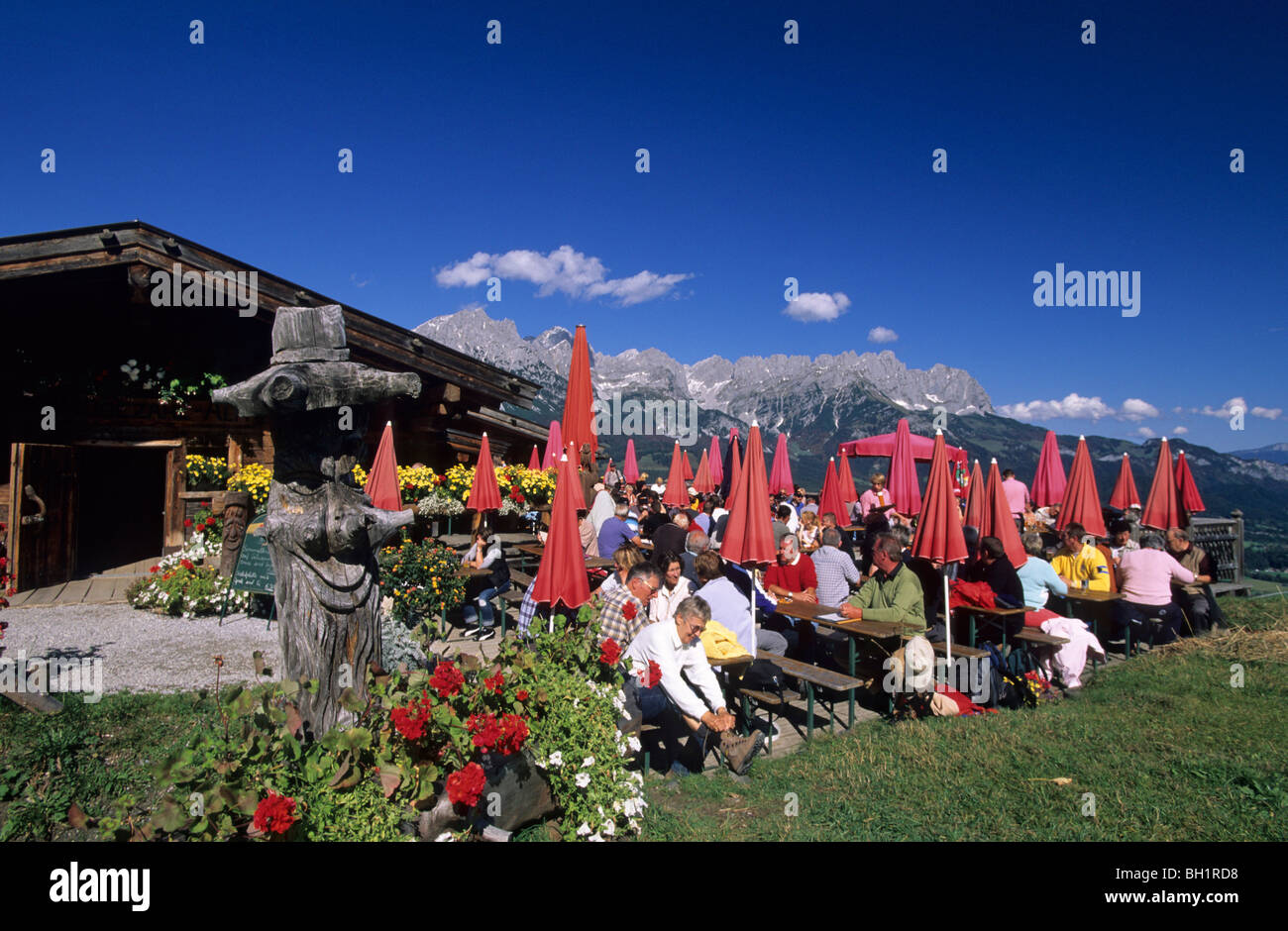 hikers on terrace of alpine hut Ruebezahlalm, view to Wilder Kaiser ...