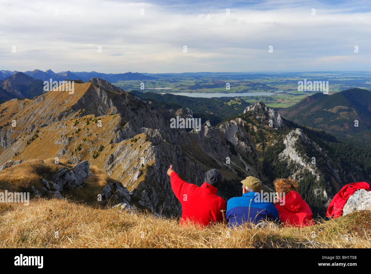 Hikers enjoying view over Ammergau Alps, lake Forggensee in background, Klammspitze, Ammergau Alps, Pfaffenwinkel, Bavaria, Germ Stock Photo