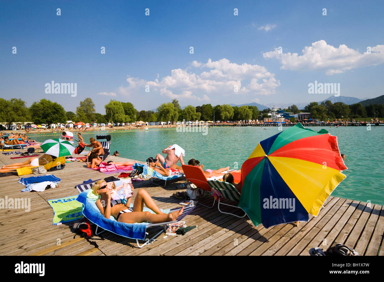 Young people sunbathing on landing stage at Strandbad Klagenfurt, Lake Woerthersee (biggest lake of Carinthia), Klagenfurt, Cari Stock Photo
