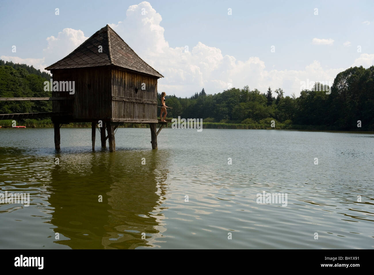 Woman standing in front of wooden hut at Lake Laengsee, Carinthia, Austria Stock Photo