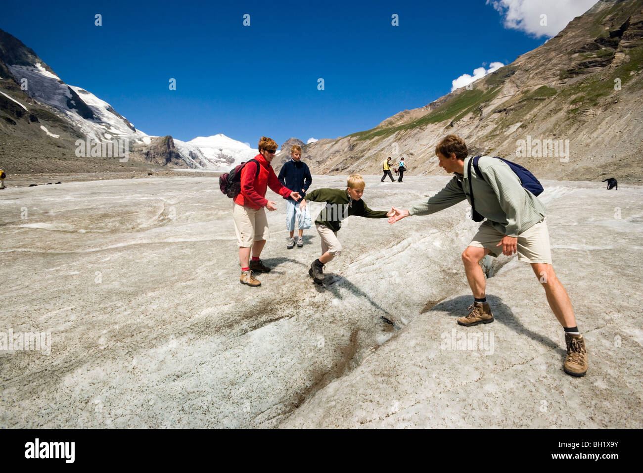 Father helping son to jump over a cleft, Pasterze glacier (the biggest glacier of Austria), Grossglockner (3798 m, highest mount Stock Photo