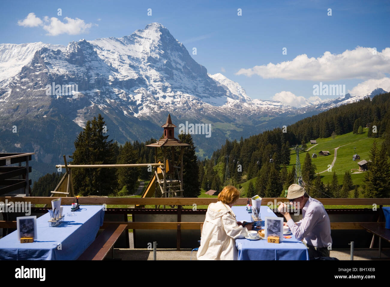 Couple sitting on terrace of the mountain restaurant Berghaus Bort (1600 m), First, Eiger (3970 m) in background, Grindelwald, B Stock Photo