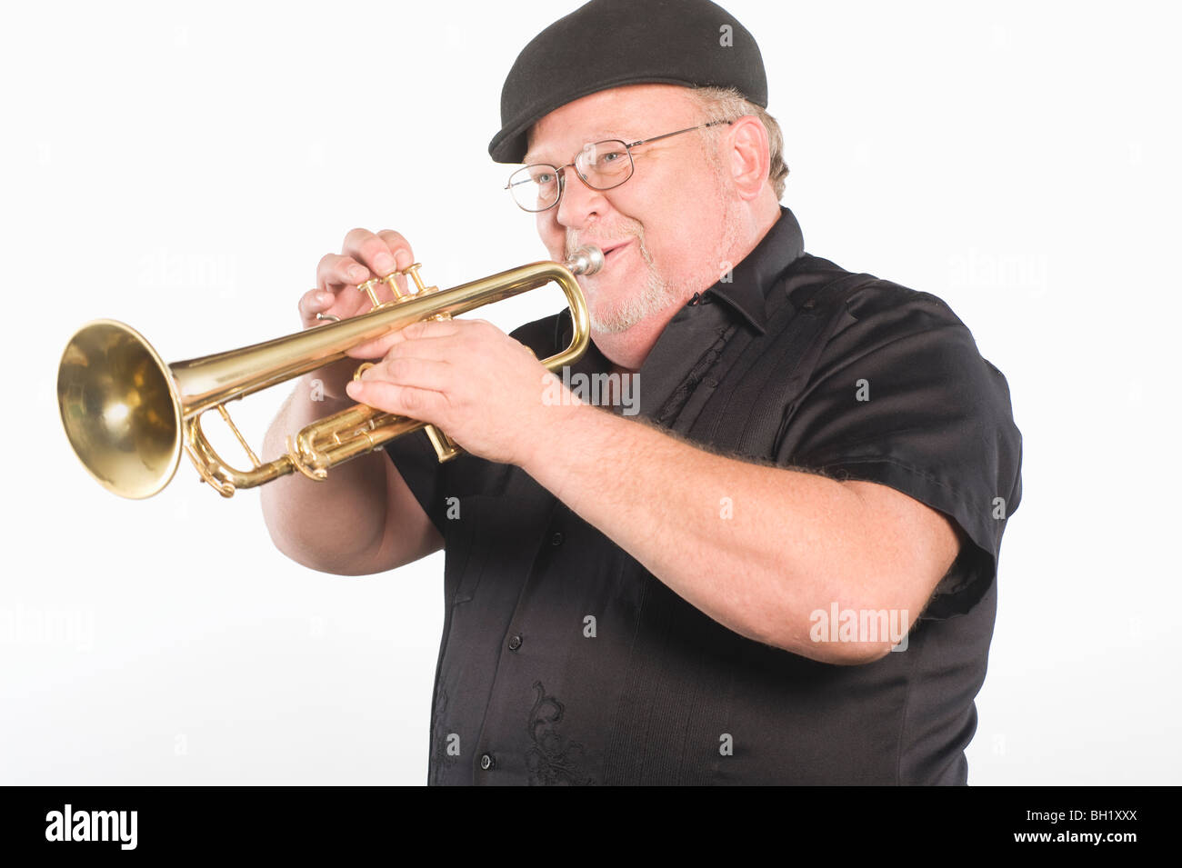 Mature man in flat cap playing the trumpet Stock Photo