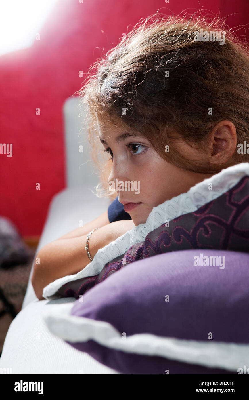9 YEARS OLD GIRL WATCHING TV LAYING ON THE SOFA INDOOR Stock Photo
