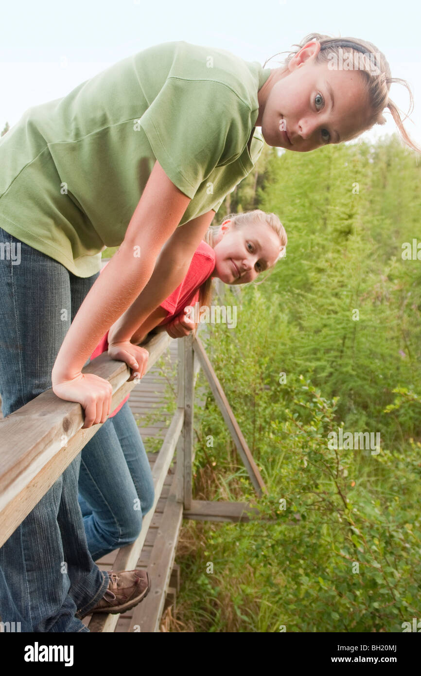 Sisters on rail of boardwalk nature trail, Riding Mountain National Park, Manitoba, Canada Stock Photo