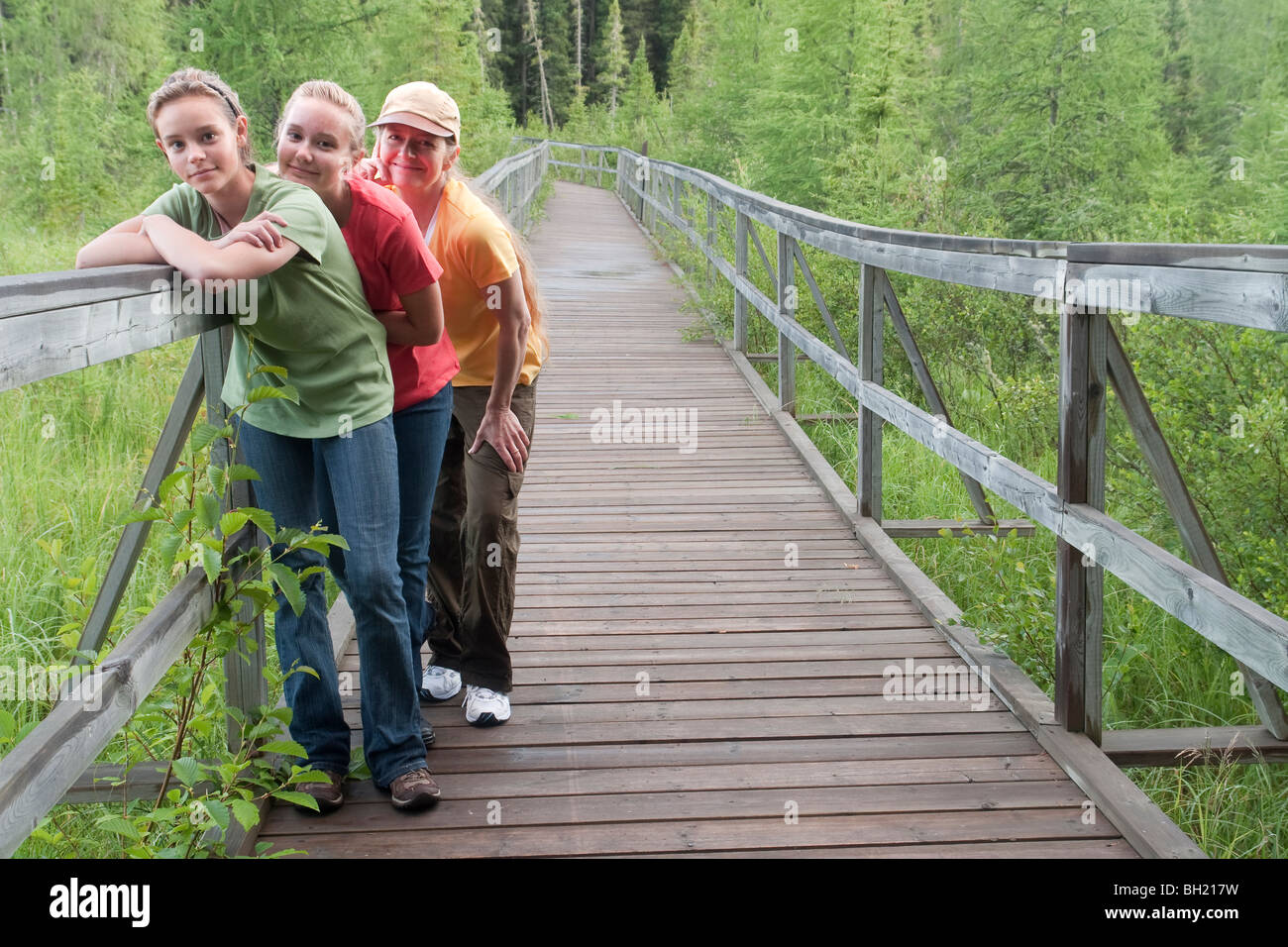 Three women posed on boardwalk nature trail, Riding Mountain National Park, Manitoba, Canada Stock Photo
