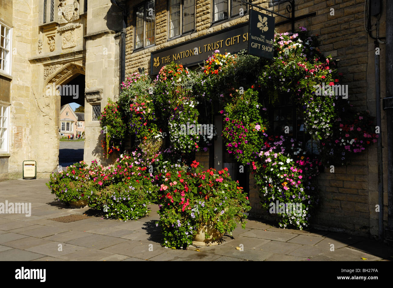 A floral display outside the National Trust gift shop by Penniless Porch in the Market Place, Wells, Somerset, England Stock Photo