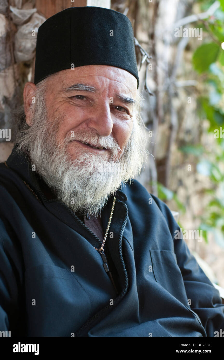 Older Greek Orthodox priest smiling with beard and robes Stock Photo