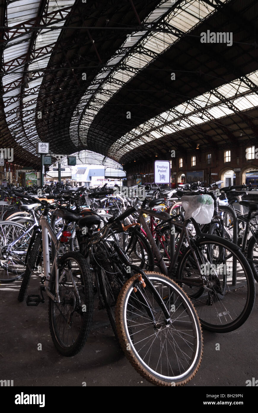 Commuters bicycles parked at the bicycle parking point inside a large British railway station with a canopy Stock Photo