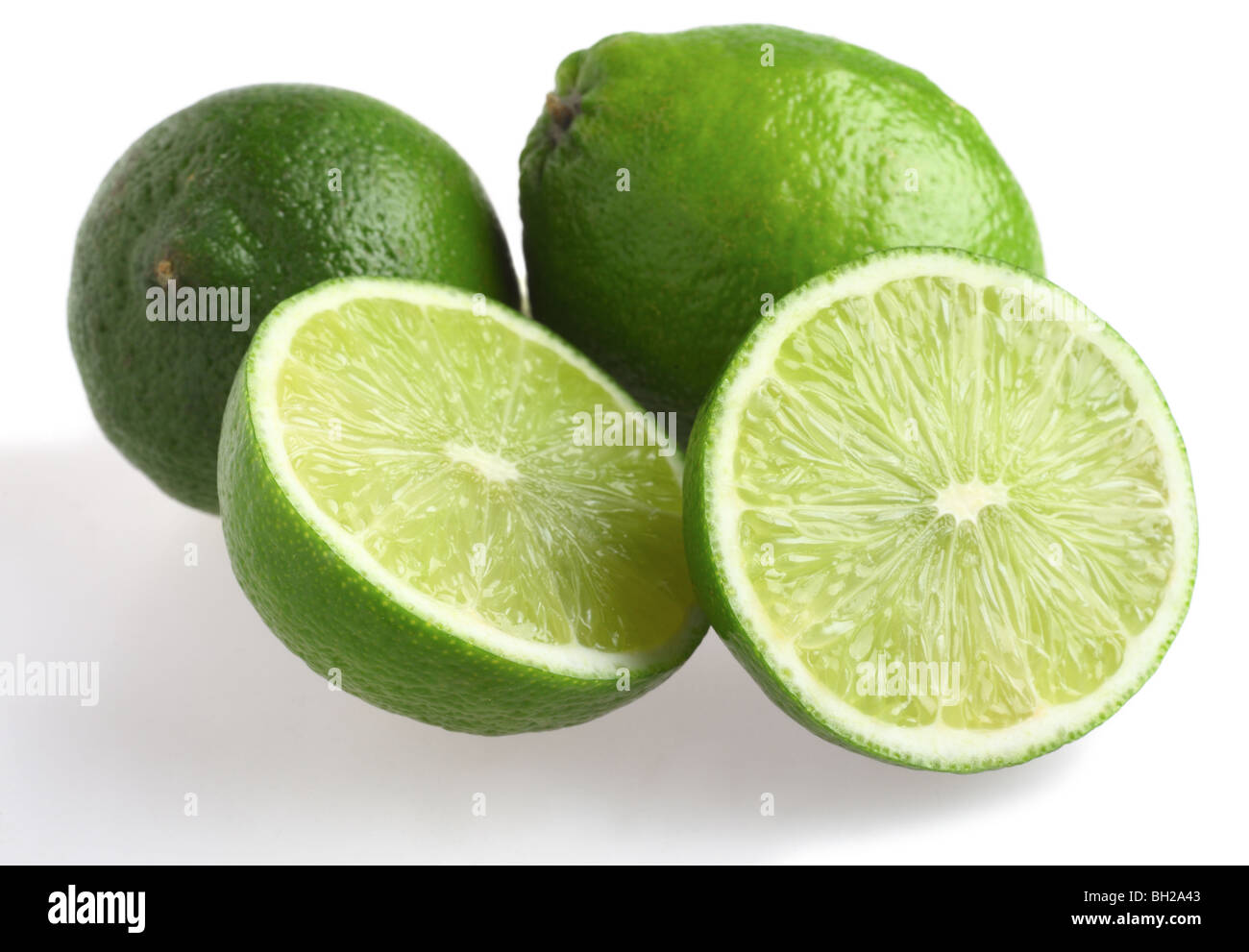 Three fresh limes, one of them cut in half, over a white background with a shadow Stock Photo