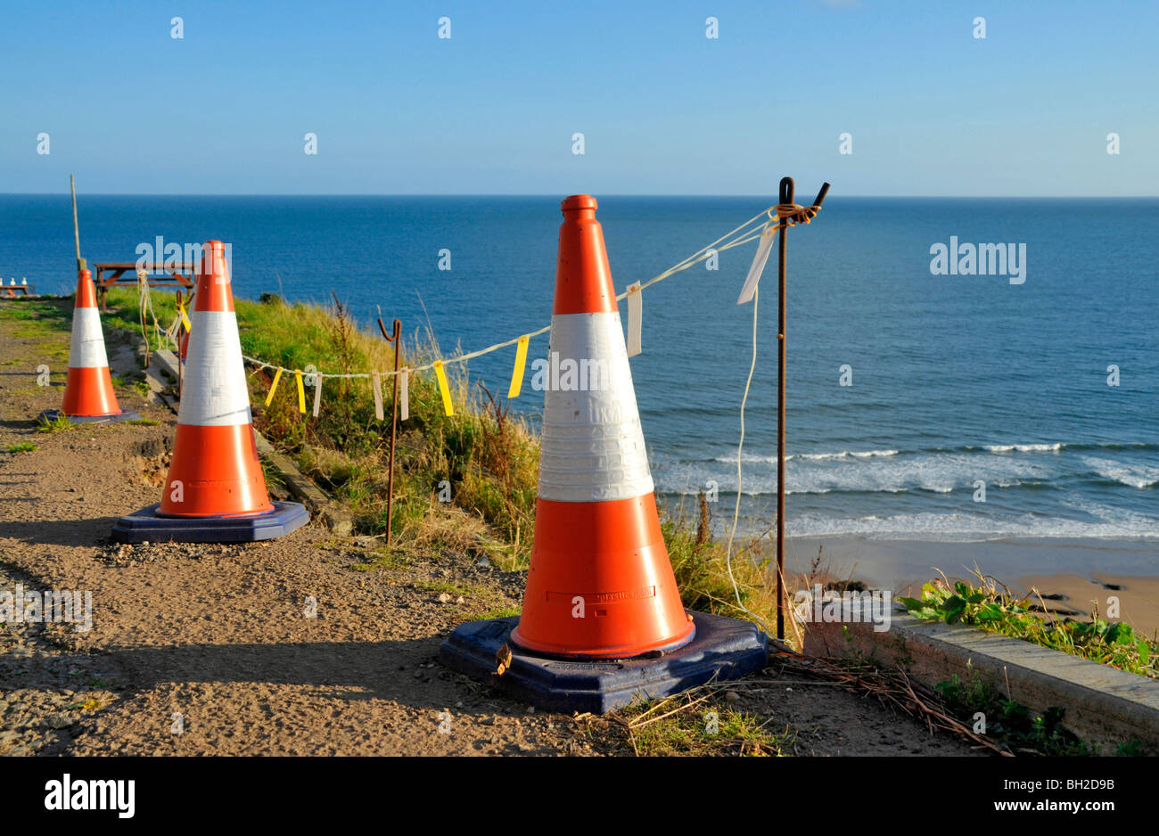 a series of traffic cones line the edge of an eroding coastal road in Scotland. Stock Photo