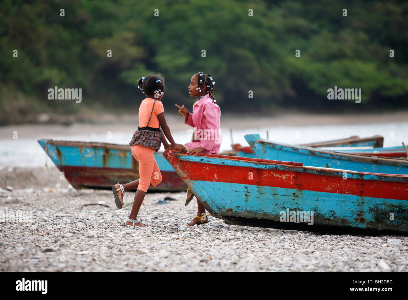 Two girls and wooden fishing boats, Bahoruco, Dominican Republic Stock Photo