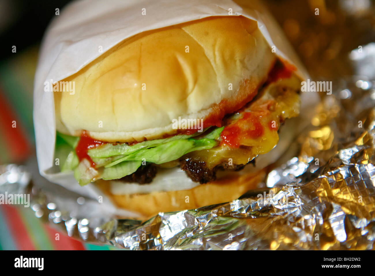 Typical New York Cheese burger, also know as Hamburger with Cheese, french fries, Coke and onion rings Stock Photo