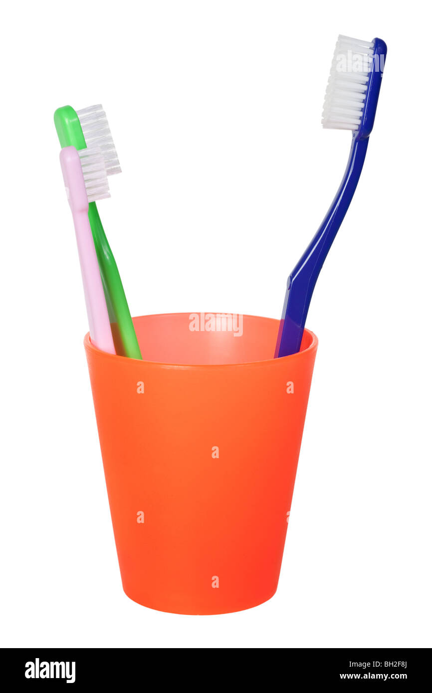 Big toothbrush opposite two little toothbrushes in a cup isolated on