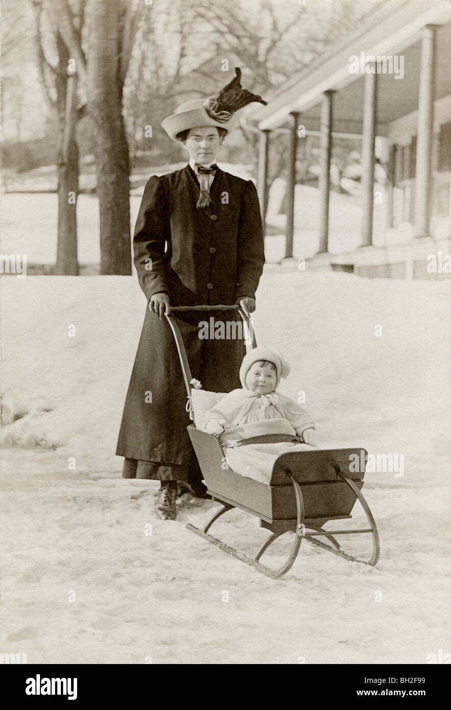 Mother Pushing Infant in the Snow in Sleigh Baby Carriage Stock Photo
