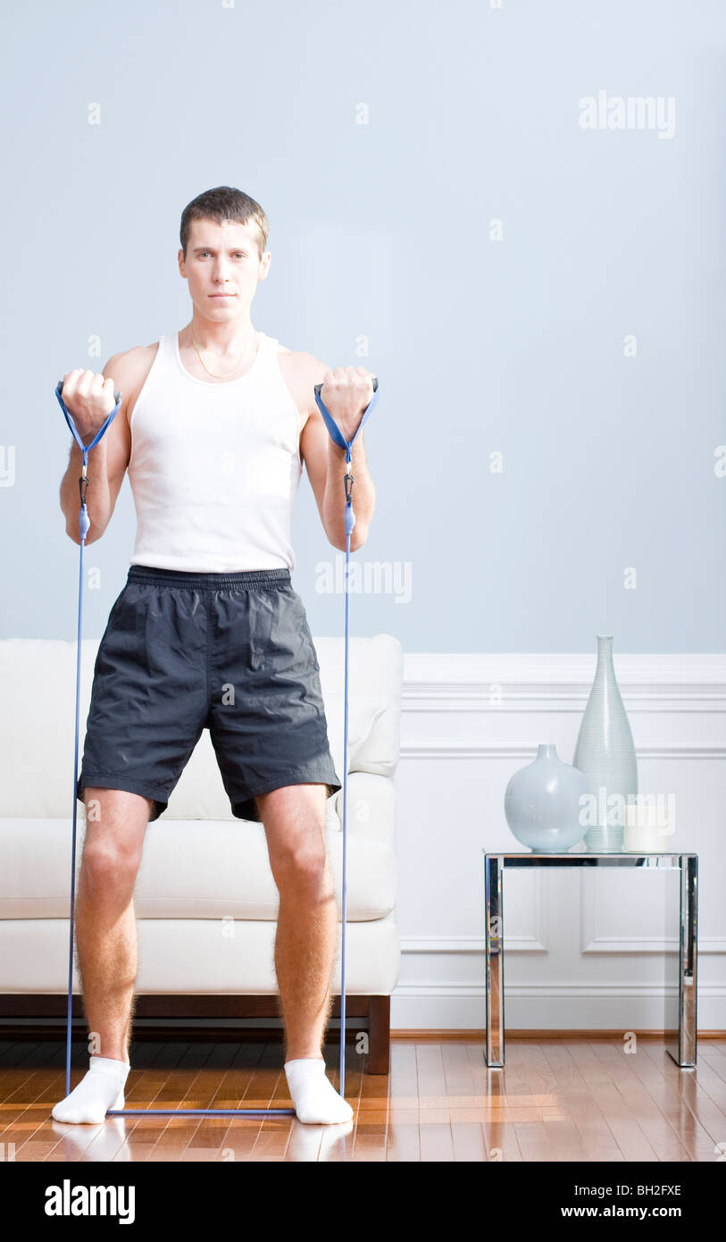 Man standing and using resistance bands in his living room. Vertical format. Stock Photo