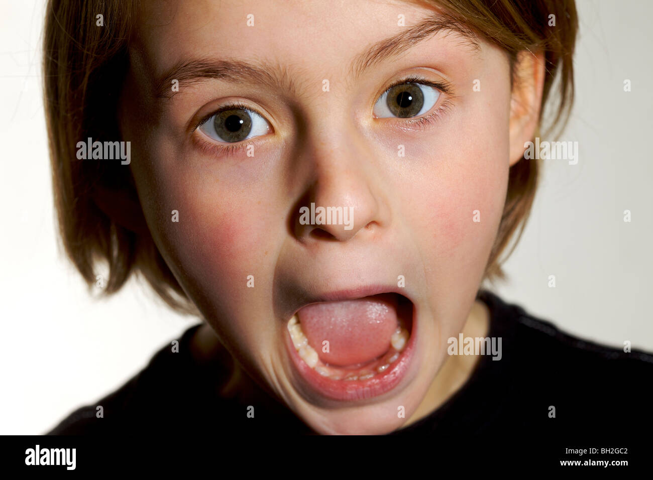 Young girl shouting screaming shocked alarmed scared surprised quizzical pull a face Stock Photo