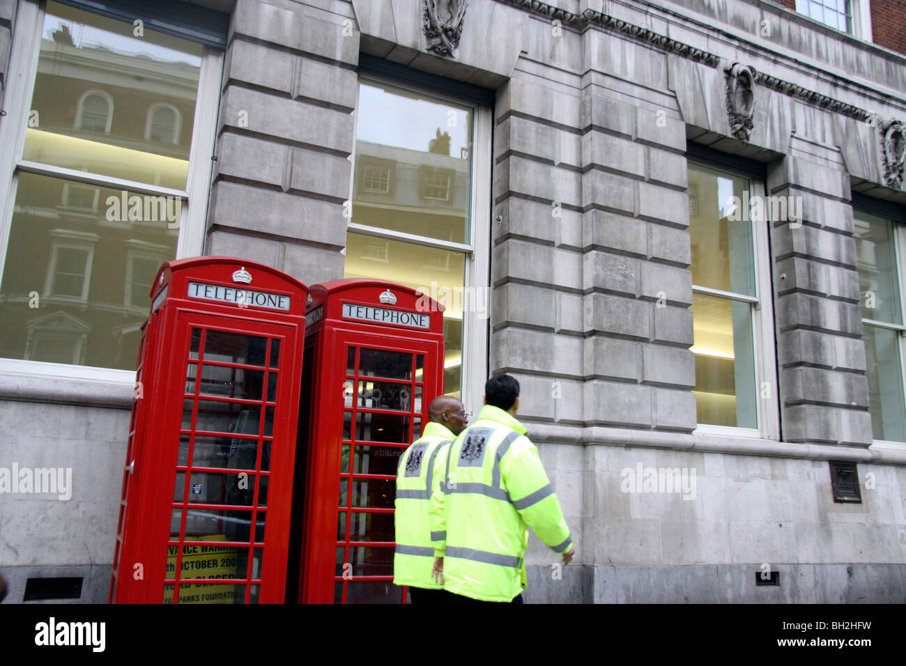 Two workers walking past telephone boxes near Whitehall in London Stock Photo