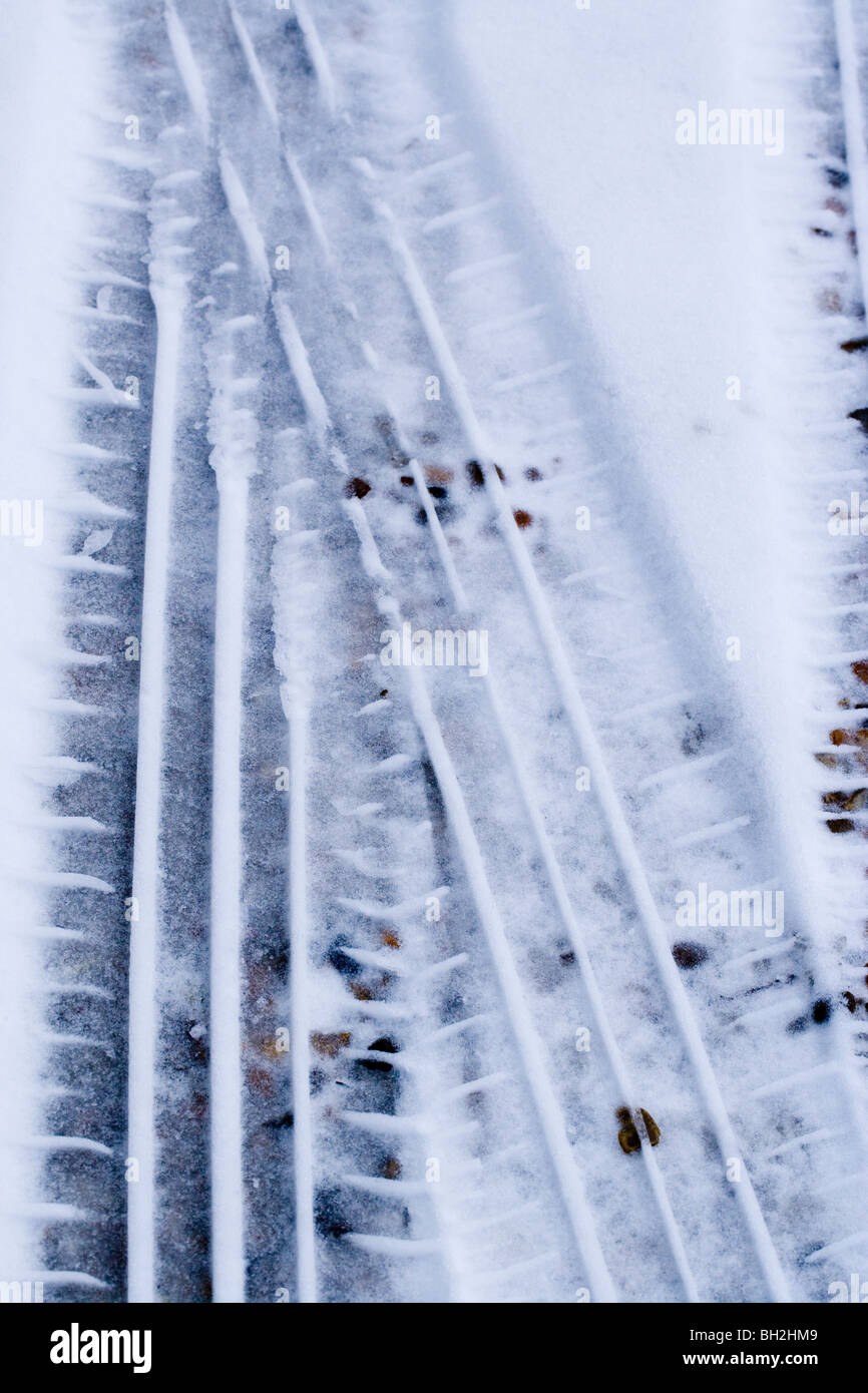 Car tyre prints in softening melting snow on a gravel road. Stock Photo