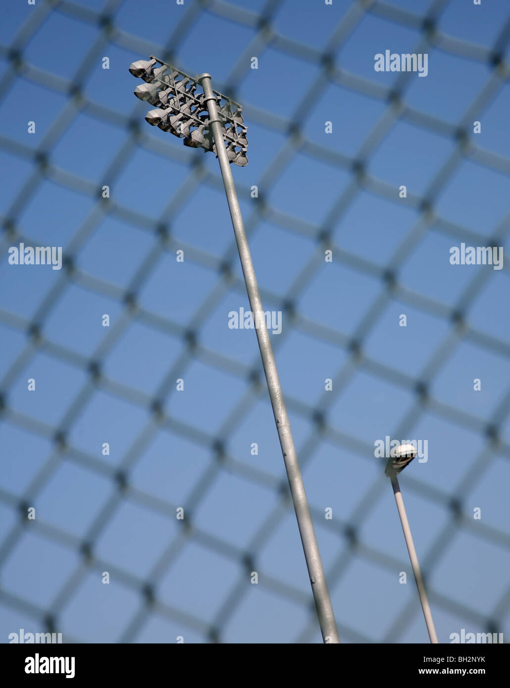 Sports ground floodlighting with mesh fence Stock Photo