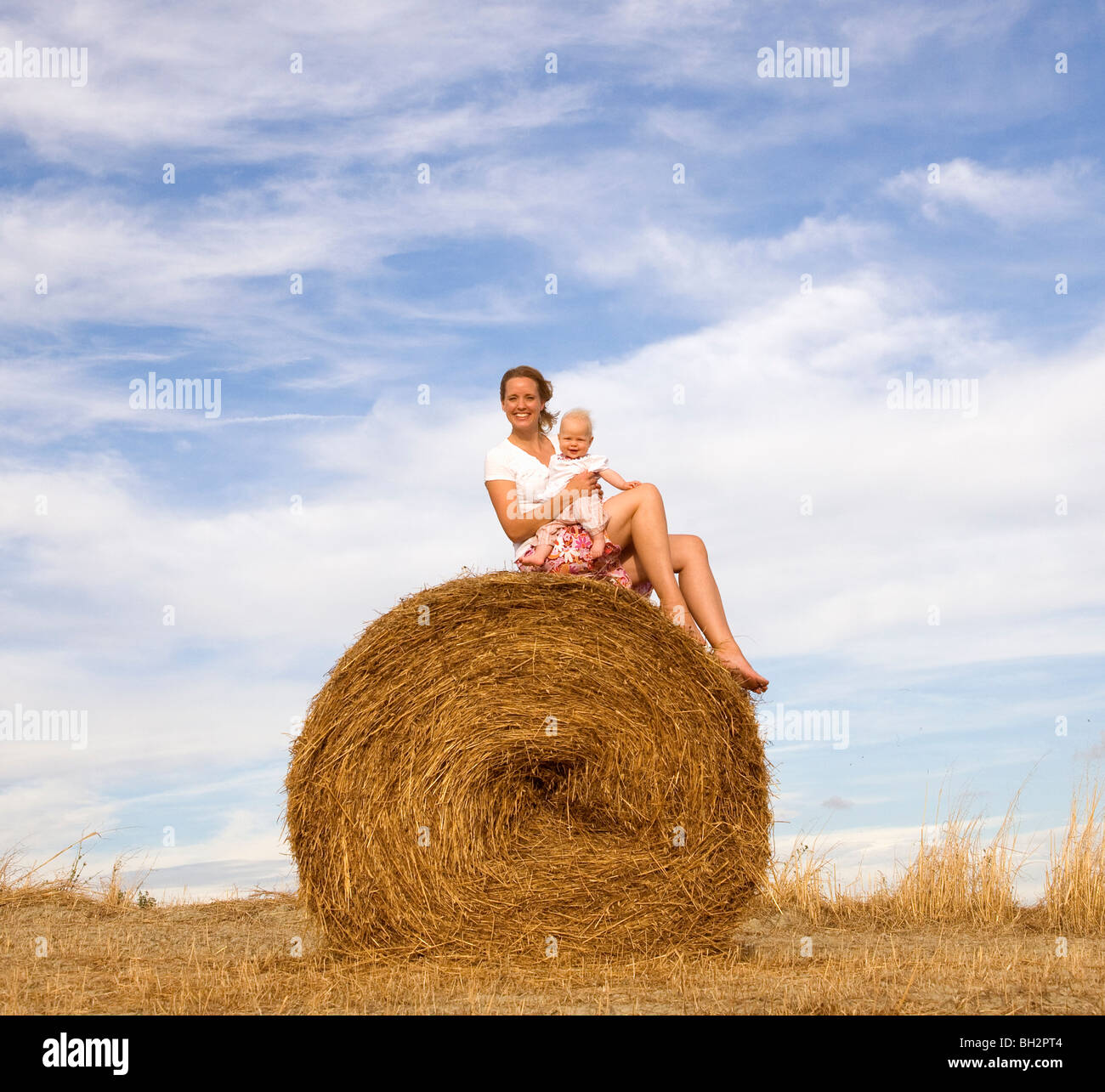woman holding baby on hay bale Stock Photo