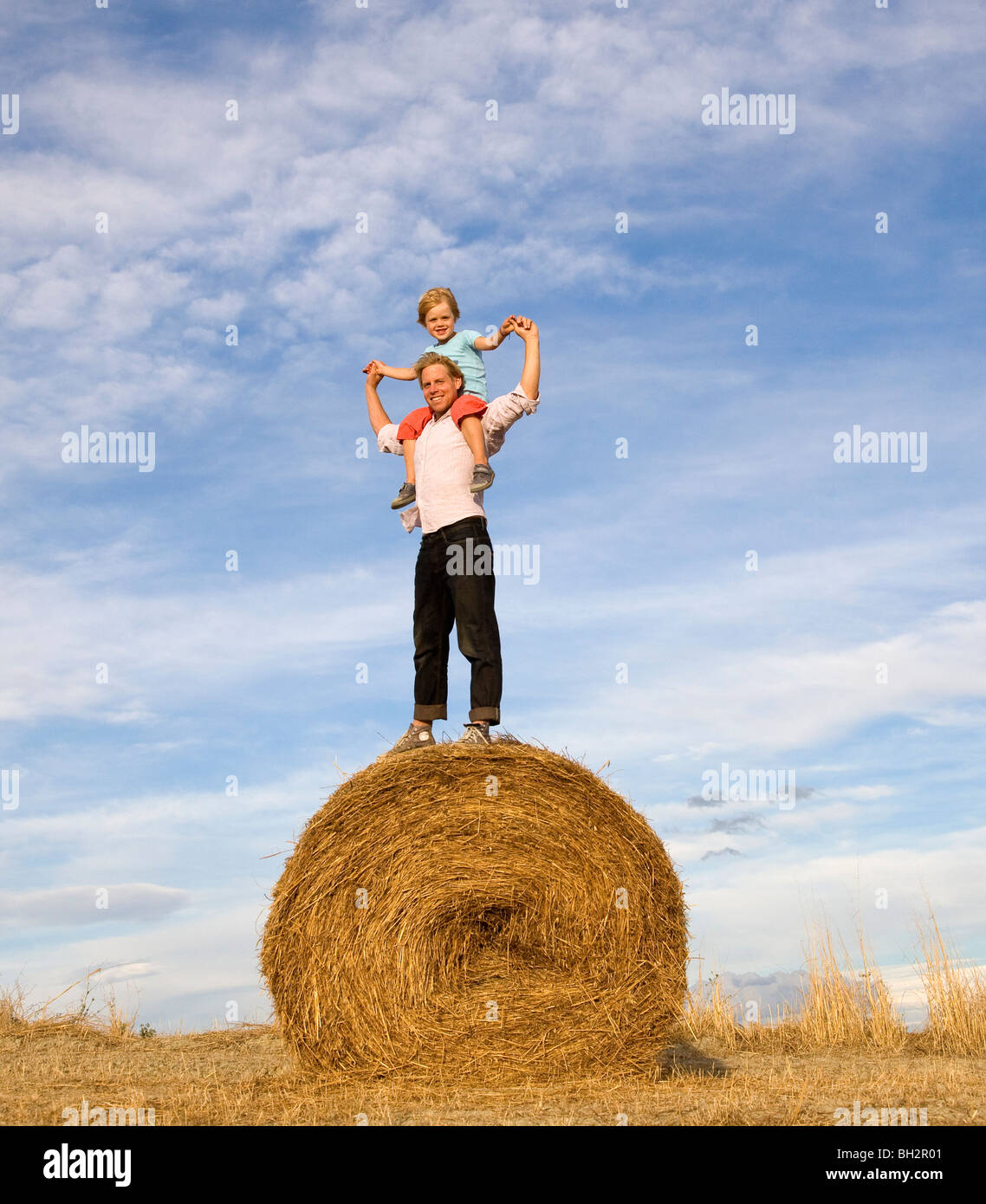 man and boy standing on hay bale Stock Photo