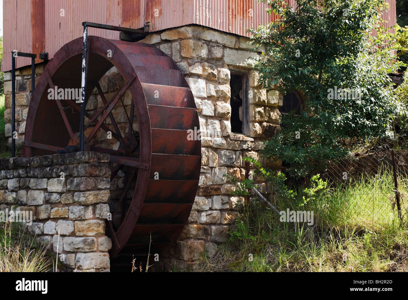 Old steel water wheel on a stone and tin watermill. Kwazulu Natal, South Africa. Stock Photo