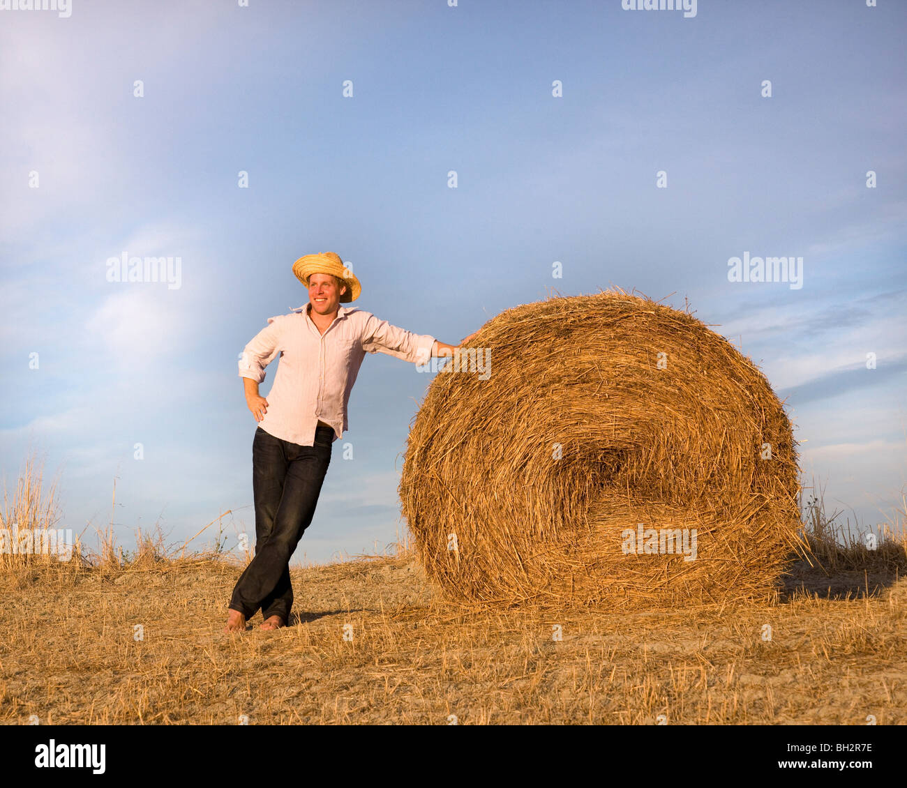 man standing by hay bale Stock Photo