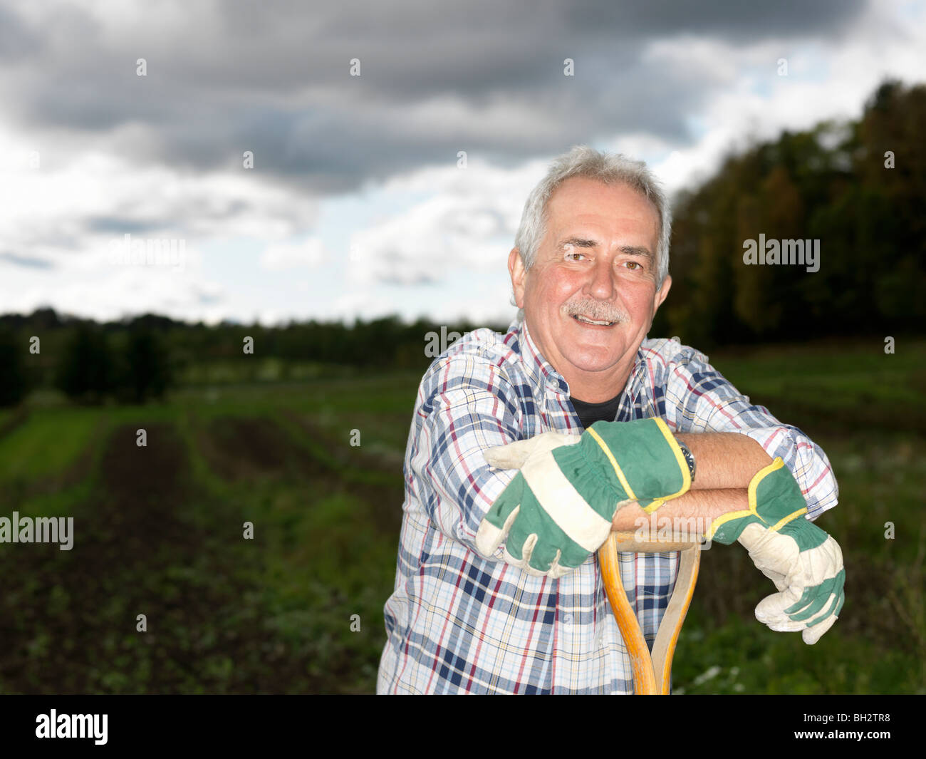 Mature man resting on shovel Stock Photo