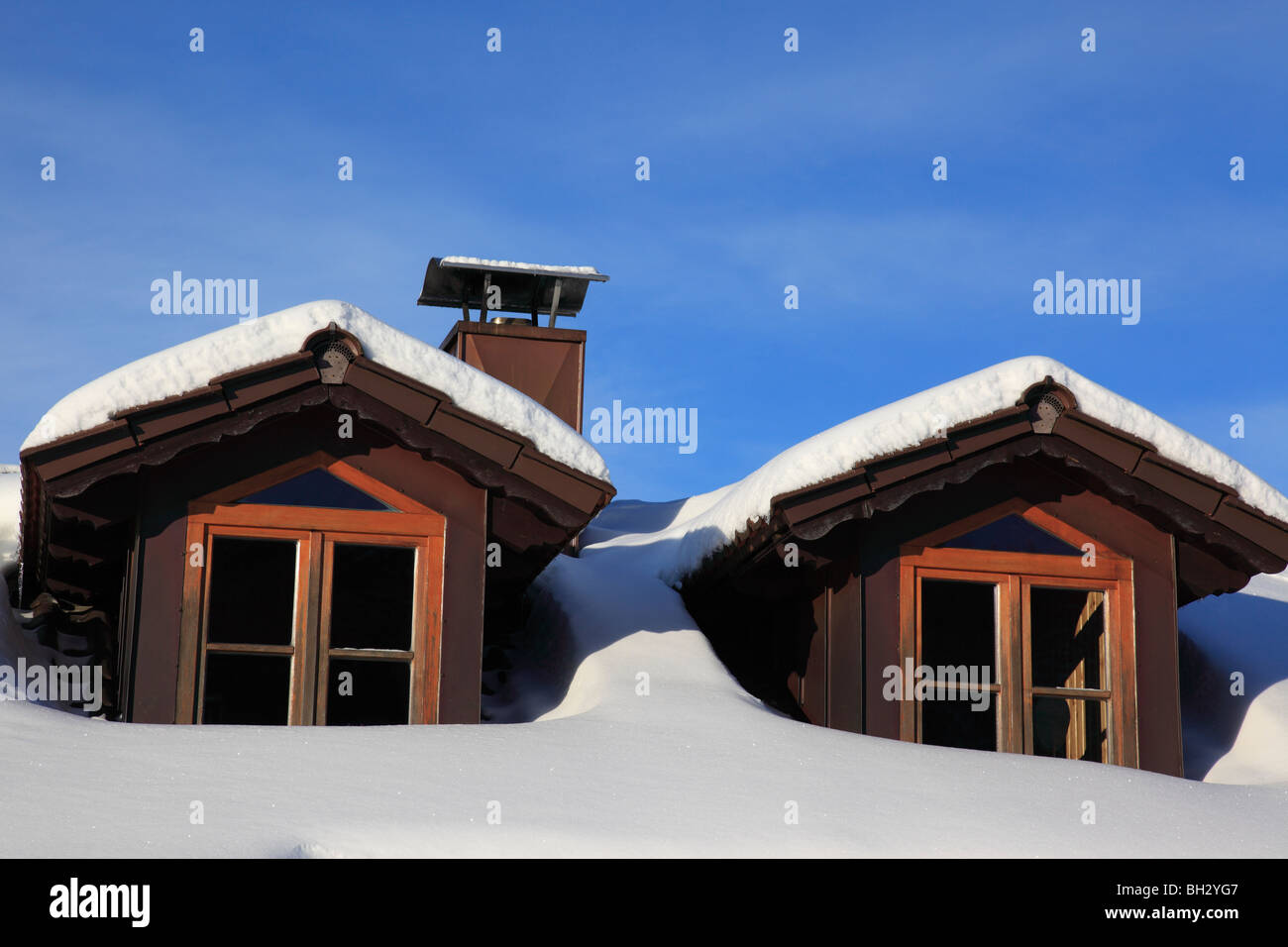 two attic windows on roof of Bavarian House in winter, covered by snow ...